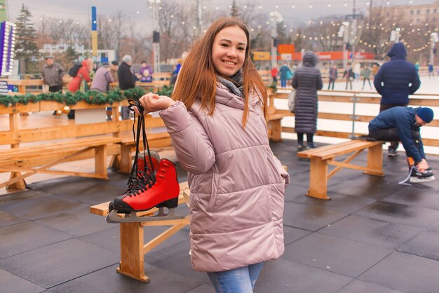 jonge mooie vrouw op een ijsbaan met schaatsen in haar handen