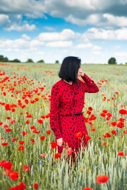 Jonge mooie vrouw op het veld van de zomerbloemen klaprozen