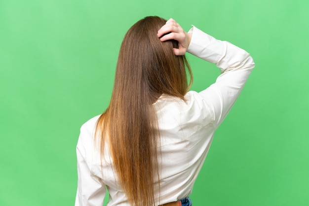 Jonge mooie vrouw over geïsoleerde chroma key achtergrond in rugpositie en denken