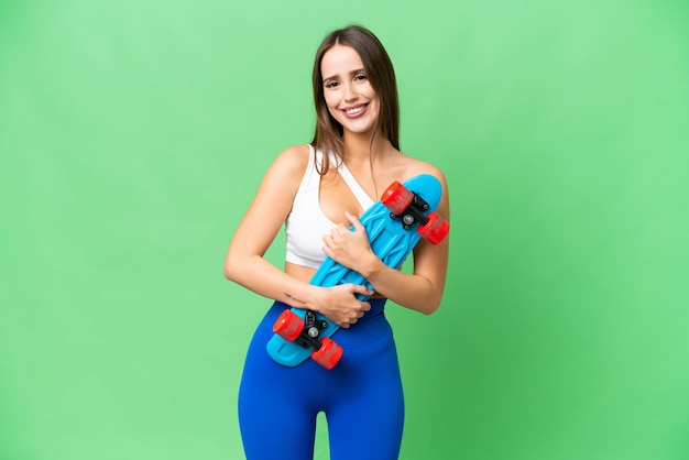 Jonge mooie vrouw over geïsoleerde chroma key achtergrond met een skate met een gelukkige uitdrukking