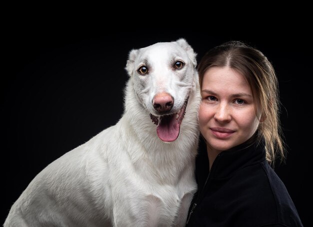 Jonge mooie vrouw poseert met haar petwhite gemarkeerd op een zwarte achtergrond