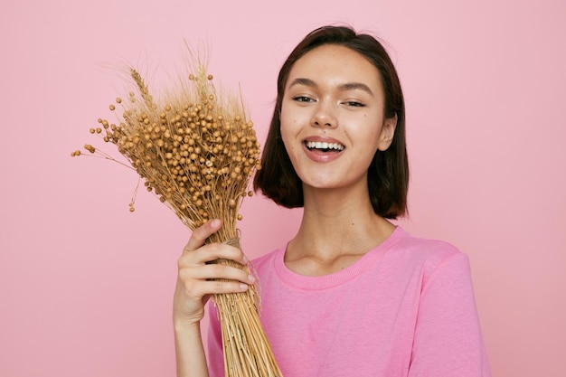 Jonge mooie vrouw roze t-shirts boeket van gedroogde bloemen geïsoleerde achtergrond