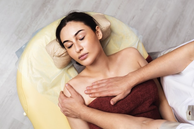 Jonge mooie vrouw rust tijdens een massageprocedure op het gebied van het sleutelbeen in de spa-salon