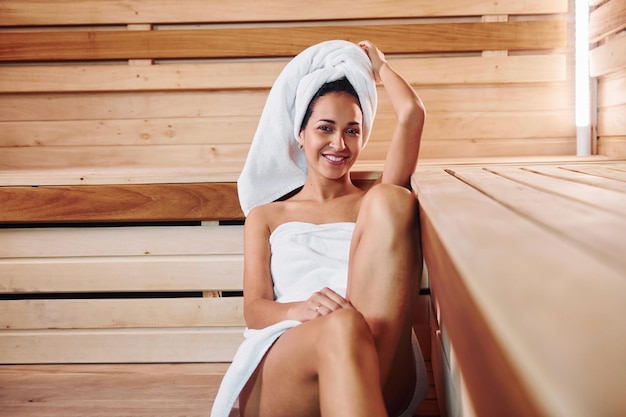 Jonge mooie vrouw rust uit in de sauna. Conceptie van lichaamsverzorging.