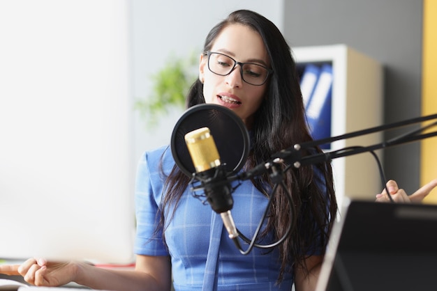 Jonge mooie vrouw spreekt in microfoon op werkplek werk radio host concept