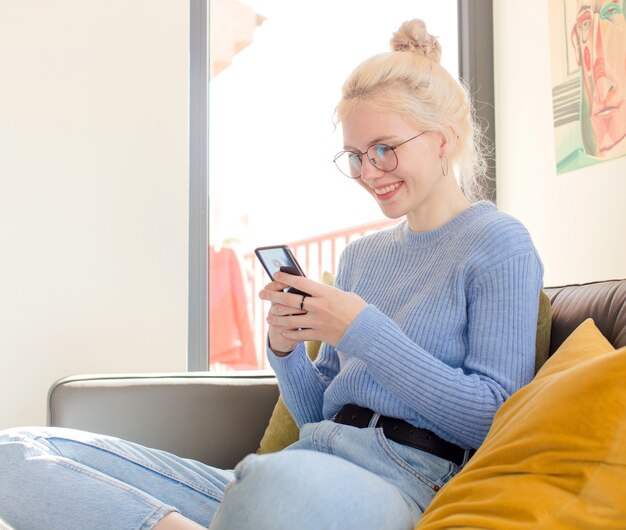 Jonge mooie vrouw thuis met behulp van een telefoon