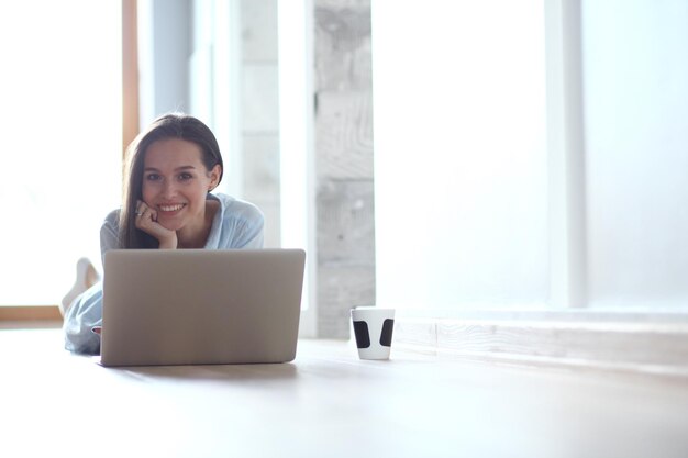 Jonge mooie vrouw thuis zittend op de vloer met laptop Jonge mooie vrouw