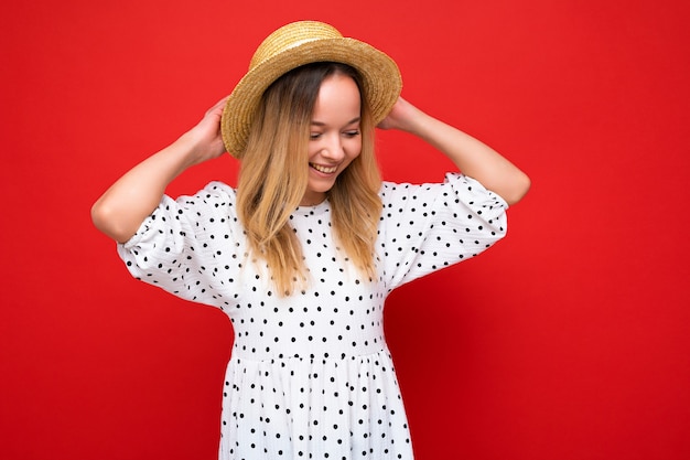 Jonge mooie vrouw trendy vrouw in casual zomerjurk en strohoed positieve vrouw toont gezichtsbehandeling