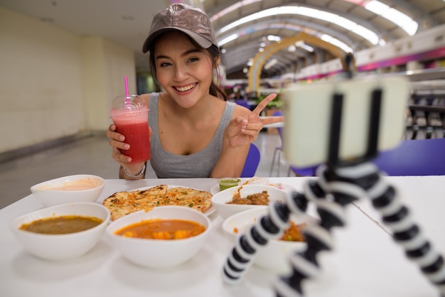 Jonge mooie vrouw vloggen met mobiele telefoon in restaurant