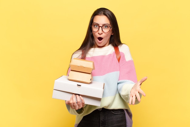 Jonge mooie vrouw voelt zich extreem geschokt en verrast, angstig en in paniek, met een gestrest en geschokte blik. neem een fastfoodconcept