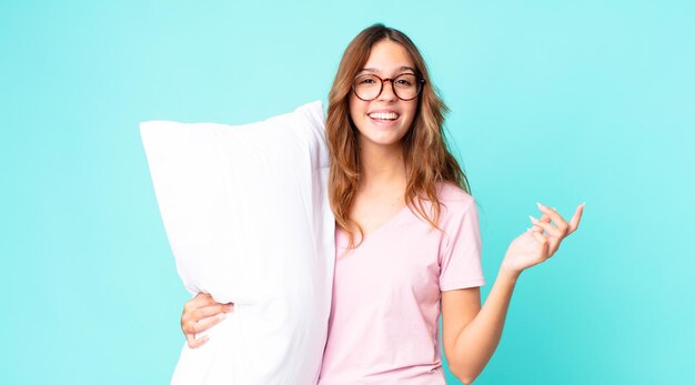 Jonge mooie vrouw voelt zich gelukkig, verrast en realiseert zich een oplossing of idee met een pyjama en een kussen vast