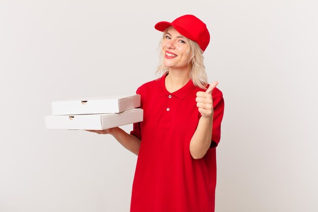 Jonge mooie vrouw voelt zich trots, positief glimlachend met duimen omhoog. pizza bezorgconcept