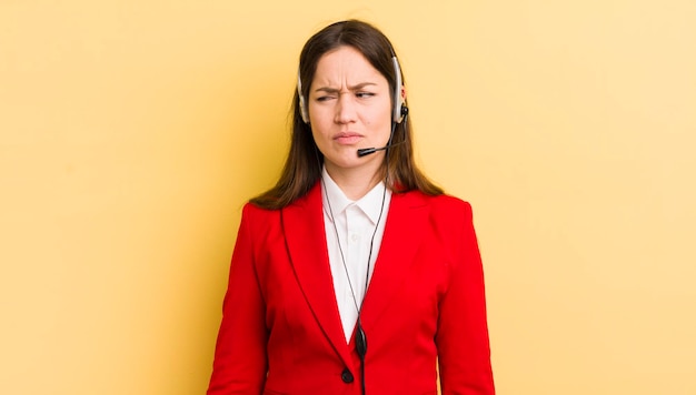 Jonge mooie vrouw voelt zich verdrietig, boos of boos en kijkt naar het concept van de telemarketeer aan de zijkant