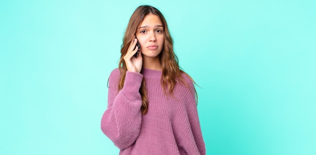 Jonge mooie vrouw voelt zich verdrietig en zeurt met een ongelukkige blik en huilt en gebruikt een smartphone