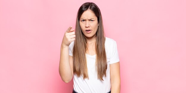 Jonge mooie vrouw wijzend op camera met een boze agressieve uitdrukking die eruit ziet als een woedende, gekke baas