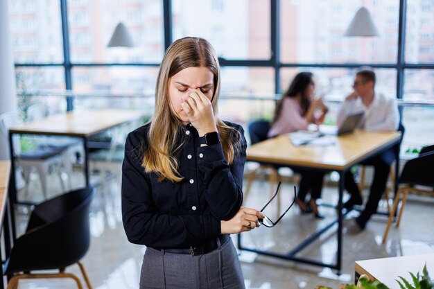 Jonge mooie vrouw zakenvrouw lijdt aan hoofdpijn door overwerk migraine op het werk