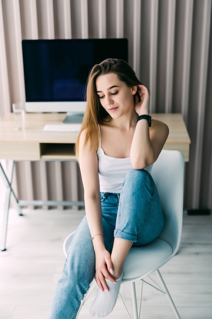 Jonge mooie vrouw zittend op de stoel thuis