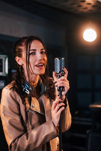 Jonge mooie vrouwelijke artiest zingt en repeteert in een opnamestudio