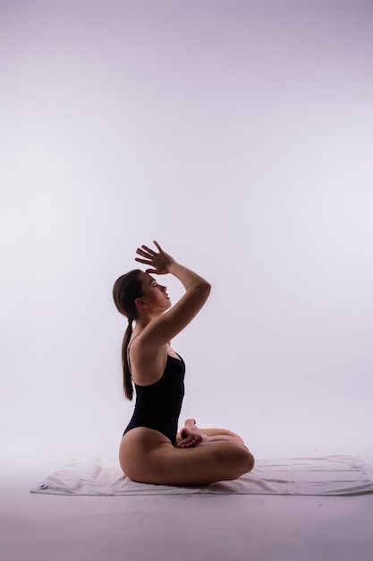 Foto jonge mooie vrouwelijke yoga poseert op een grijze studio achtergrond