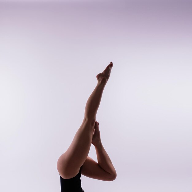 Jonge mooie vrouwelijke yoga poseert op een grijze studio achtergrond