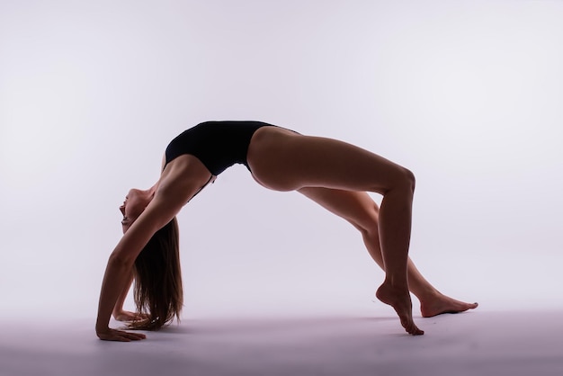 Jonge mooie vrouwelijke yoga poseert op een grijze studio achtergrond