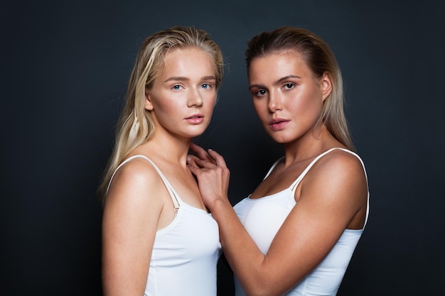 Jonge mooie vrouwen met natuurlijke heldere huid en blonde haren Twee modellen dragen wit overhemd