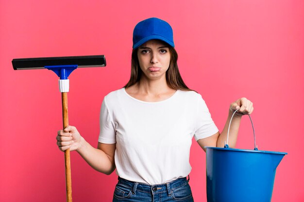 Jonge mooie vrouwenhuishoudster die de vensters schoonmaakt