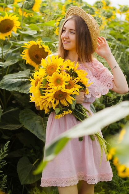 Jonge mooie vrouwentribunes onder bloeiende zonnebloemen