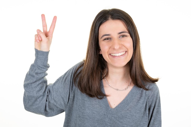 Jonge mooie zakenvrouw in geïsoleerde witte achtergrond glimlachend met blij gezicht doen v vingers overwinning teken en nummer twee