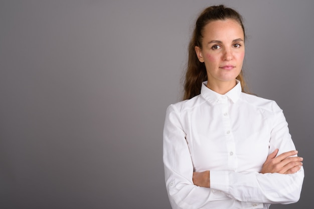 Jonge mooie zakenvrouw tegen een grijze achtergrond