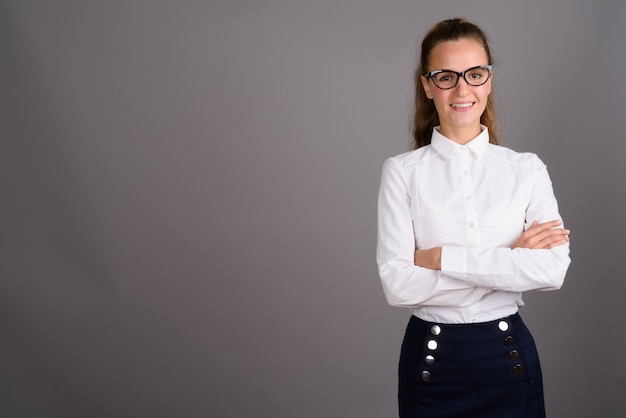 Jonge mooie zakenvrouw tegen een grijze achtergrond