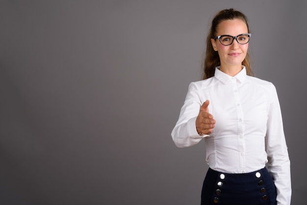 Jonge mooie zakenvrouw tegen een grijze achtergrond