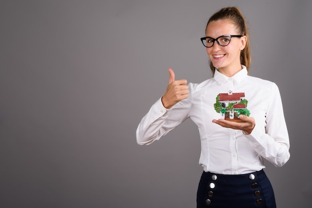 Jonge mooie zakenvrouw tegen een grijze achtergrond