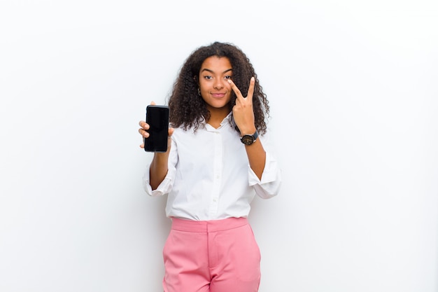 Jonge mooie zwarte met een slimme telefoon tegen witte muur