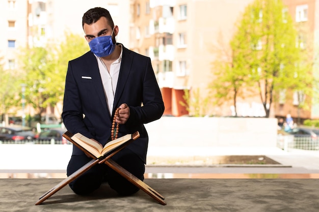 Jonge moslim man bidden in moskee met chirurgisch masker en handschoenen