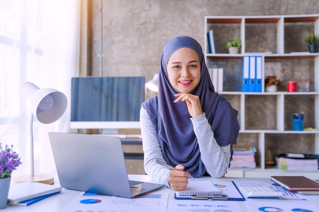 Jonge moslimvrouw die in een bedrijfskantoor werkt en hijab draagt, werkt als een startend MKB-project Looking Camera