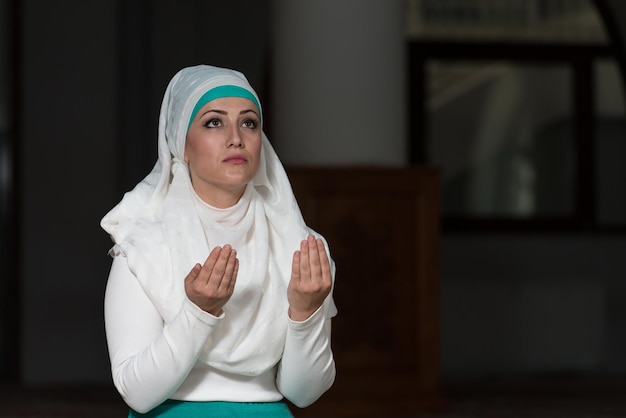 Jonge moslimvrouw die in moskee bidt