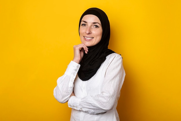 Jonge moslimvrouw in hijab glimlachend op een gele achtergrond Banner
