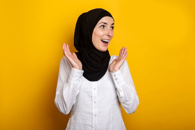 Jonge moslimvrouw in hijab met een verbaasd gezicht op geel