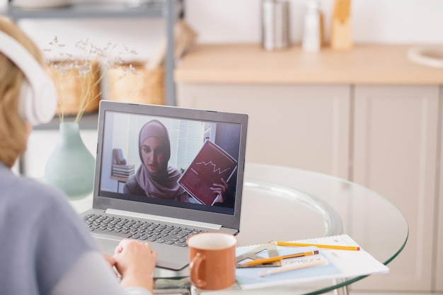 Jonge moslimvrouw met financieel document op laptopscherm