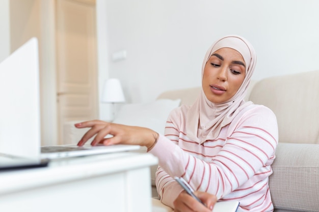 Jonge moslimvrouwen dragen hijab met typen en controleren om het klantadres op de computerlaptop thuis 's ochtends te bestellen Concept zaken klein en online winkelen