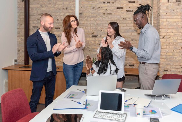 Jonge multi-etnische groep ondernemers die samenwerken voor zakelijk succes of prestatie applaudisseren in een werkkantoor multiraciale werknemers applaudisseren opgewonden voor goed nieuws