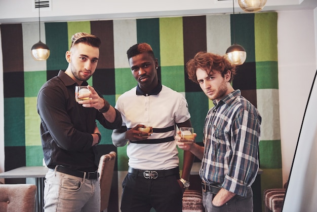 jonge multi-etnische mensen vieren en het drinken van whisky toast