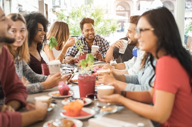 Foto jonge multiraciale mensen brunchen en drinken smoothies in bar-restaurant - focus op aziatische man gezicht