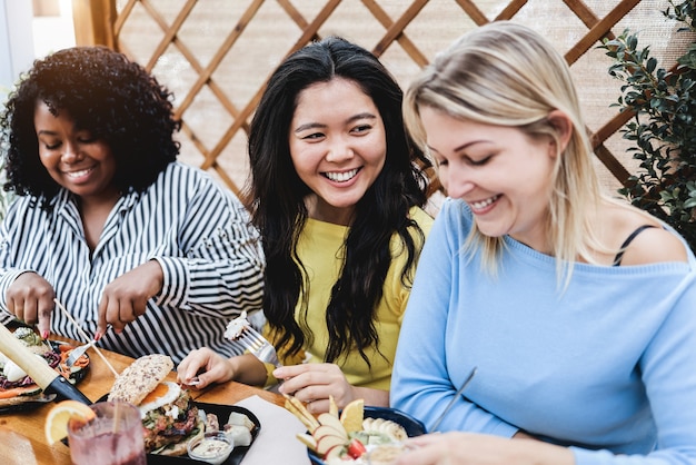 Jonge multiraciale mensen die buiten ontbijten in het terrasrestaurant - Focus op het gezicht van een Aziatisch meisje