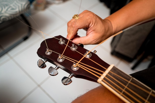 Jonge muzikant die de snaren van een klassieke gitaar verandert in een gitaarwinkel
