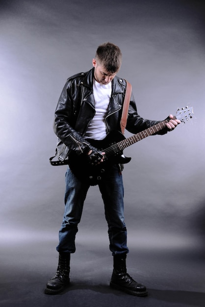 Jonge muzikant gitaar spelen op grijze achtergrond