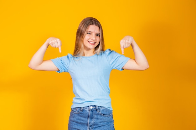 Jonge natuurlijke blanke vrouw wijst naar beneden met vingers, positief gevoel.