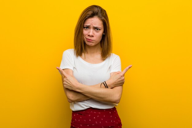 Jonge natuurlijke blanke vrouw wijst zijwaarts, probeert te kiezen tussen twee opties.