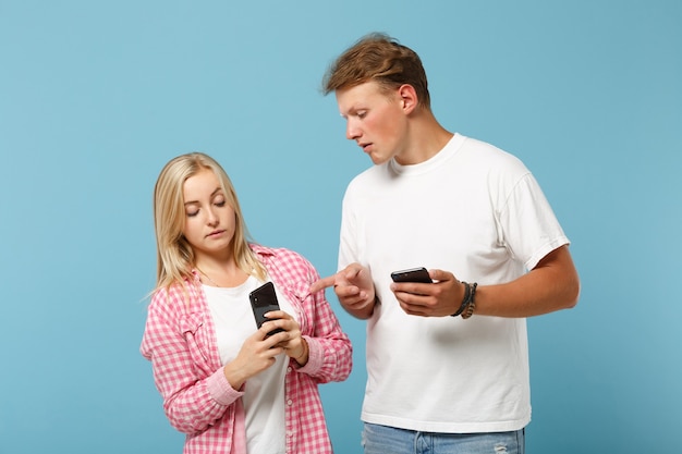 Jonge nieuwsgierige paar vrienden man en vrouw in wit roze lege lege t-shirts poseren